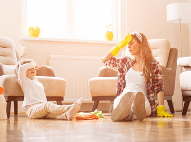 Mother and daughter on the living room floor with gloves tired from spring cleaning.