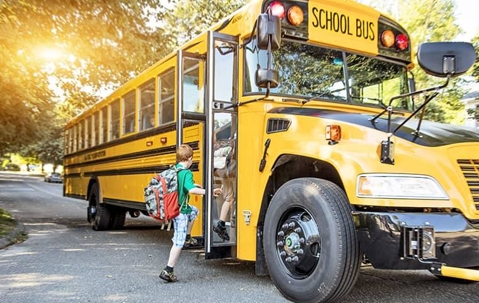 Children boarding a large yellow school bus.
